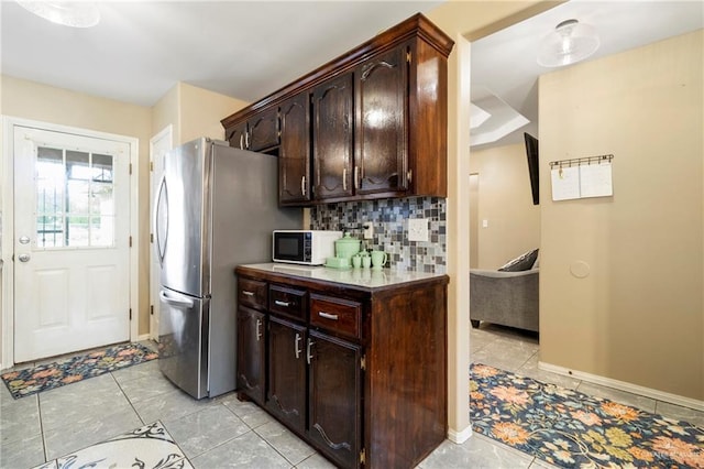 1123 E Champion St, Edinburg, TX 78539 - kitchen featuring freestanding refrigerator, dark brown cabinetry, decorative backsplash, light tile patterned floors, and baseboards
