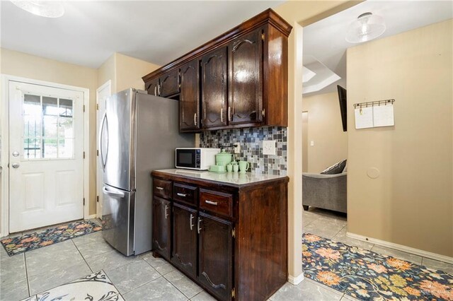 1123 E Champion St, Edinburg, TX 78539 - kitchen featuring freestanding refrigerator, dark brown cabinetry, decorative backsplash, light tile patterned floors, and baseboards