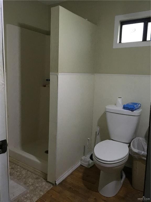 bathroom with hardwood / wood-style flooring, toilet, and walk in shower