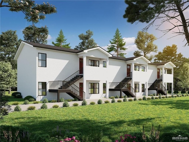 back of property with a yard, stairs, and stucco siding