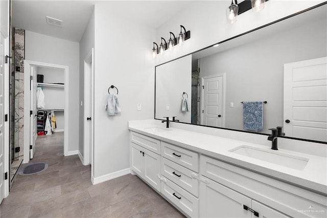 2413 S Cartier Dr, Edinburg, TX 78542 - bathroom featuring double vanity, a spacious closet, and a shower with door