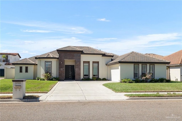 prairie-style home with a front lawn, stucco siding, a garage, and concrete driveway