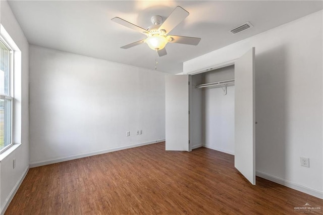 unfurnished bedroom with multiple windows, dark hardwood / wood-style floors, ceiling fan, and a closet