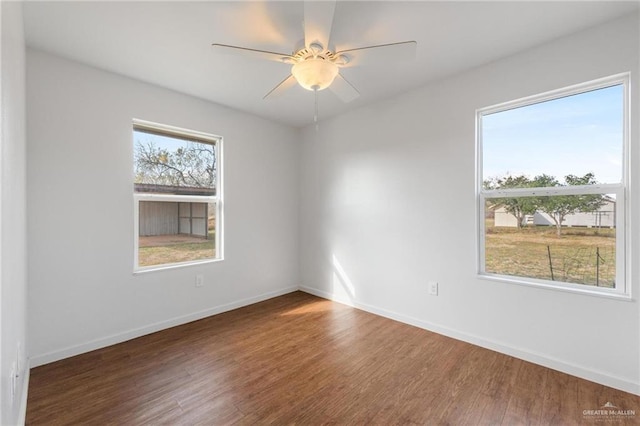 empty room with ceiling fan, plenty of natural light, and dark hardwood / wood-style floors