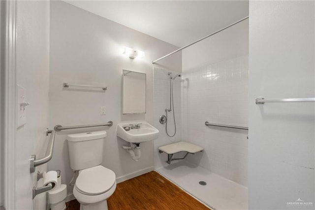 bathroom with hardwood / wood-style flooring, toilet, and tiled shower