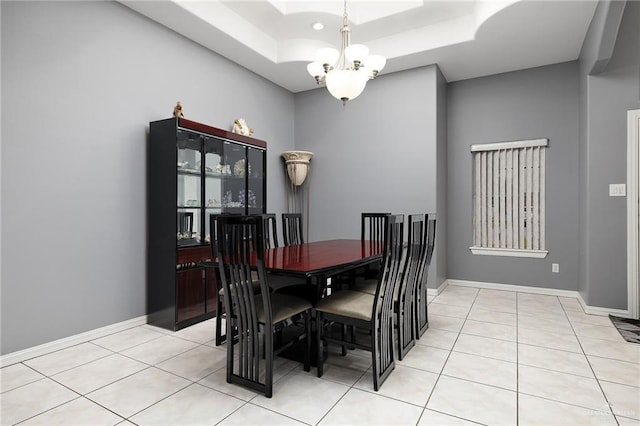 dining area with light tile patterned flooring, a raised ceiling, and a chandelier