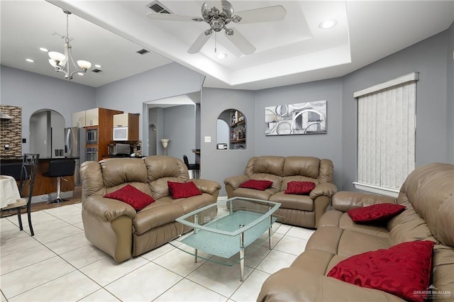 living room featuring a raised ceiling, light tile patterned floors, and ceiling fan with notable chandelier