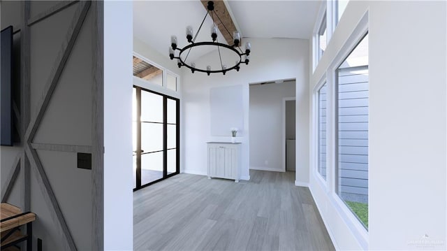 interior space with beam ceiling, a notable chandelier, a high ceiling, light wood-type flooring, and baseboards