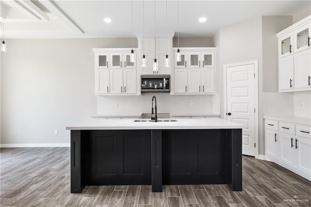 3303 Alcatraz St, Edinburg, TX 78542 - kitchen featuring a sink, stainless steel microwave, an island with sink, wood finished floors, and light countertops