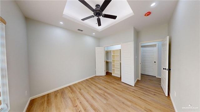 unfurnished bedroom with a walk in closet, a closet, and light wood-type flooring