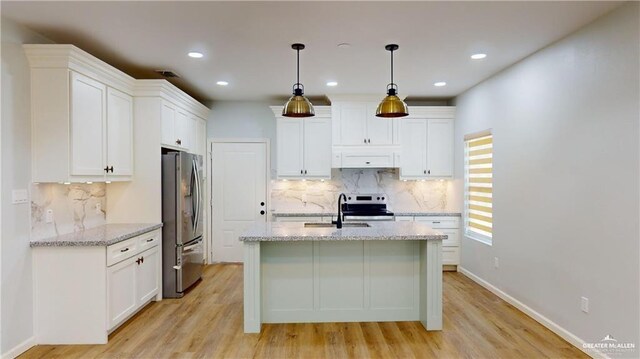 kitchen with white cabinetry, stainless steel appliances, decorative light fixtures, and light stone countertops