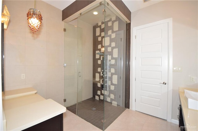 bathroom with tile patterned flooring, vanity, tile walls, and walk in shower