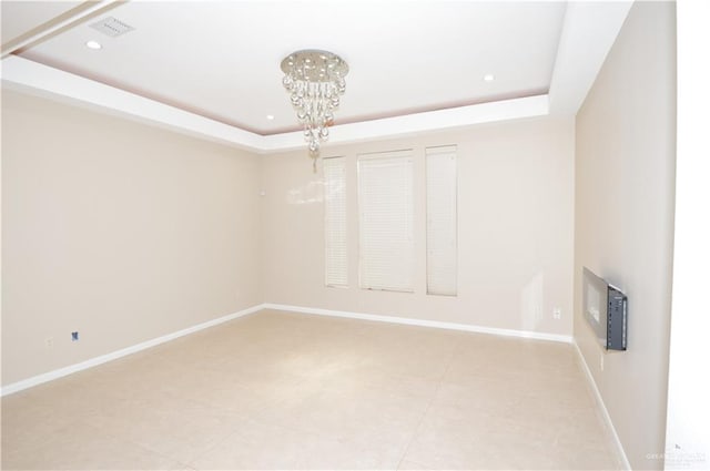 empty room with a chandelier and a raised ceiling