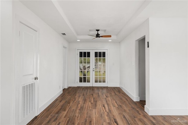 unfurnished room featuring french doors, dark hardwood / wood-style floors, ceiling fan, and a tray ceiling