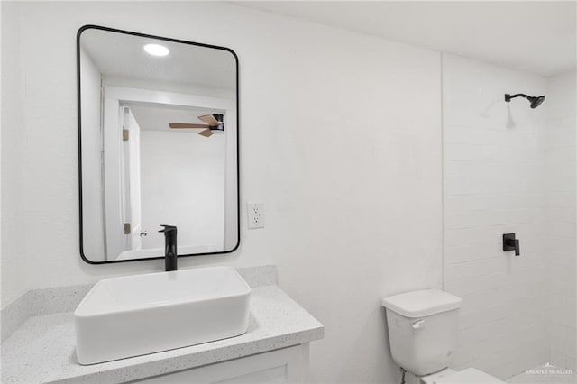 bathroom with vanity, toilet, and tiled shower