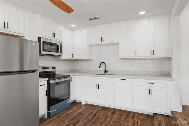 kitchen with sink, dark wood-type flooring, appliances with stainless steel finishes, tasteful backsplash, and white cabinets