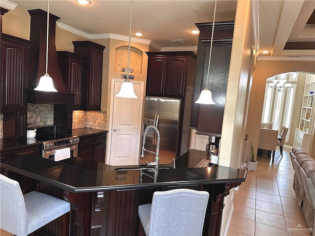 kitchen with a breakfast bar area, light tile patterned floors, stainless steel appliances, and decorative light fixtures