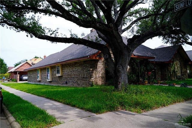 view of side of home featuring brick siding and a yard