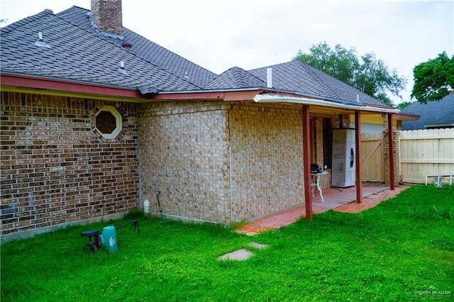view of side of home with brick siding, a chimney, and roof with shingles