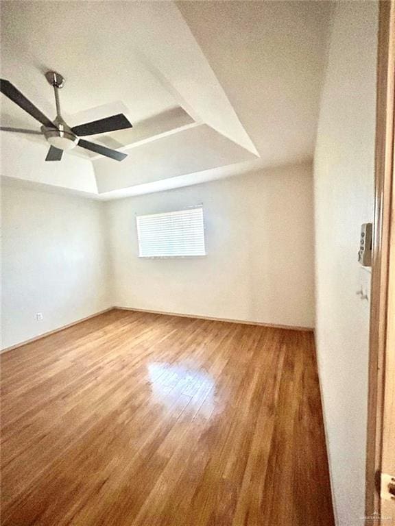 unfurnished room with ceiling fan, wood finished floors, and a raised ceiling