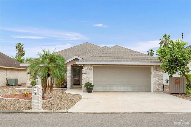 single story home with driveway, a garage, a shingled roof, central AC, and brick siding