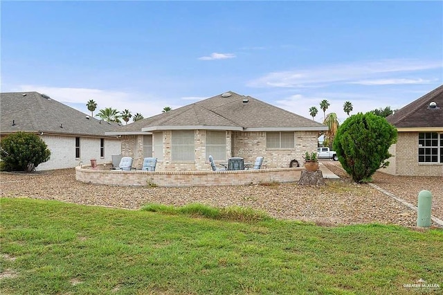 back of property featuring a shingled roof, brick siding, a patio, and a lawn