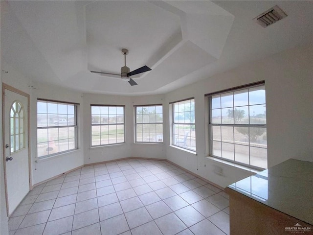 unfurnished sunroom featuring visible vents, a raised ceiling, and a ceiling fan