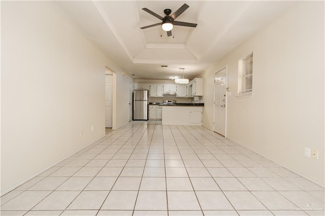 unfurnished living room featuring light tile patterned flooring, ceiling fan, and a tray ceiling