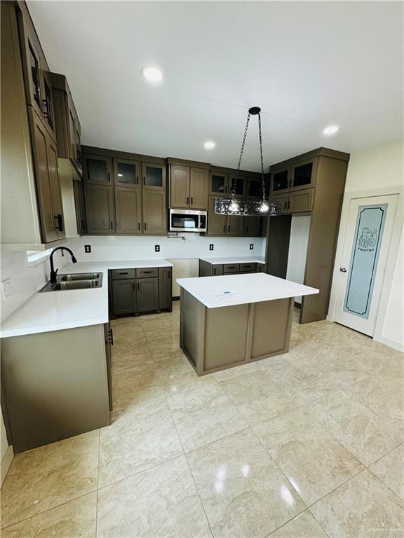 kitchen featuring dark brown cabinetry, a kitchen island, hanging light fixtures, and sink