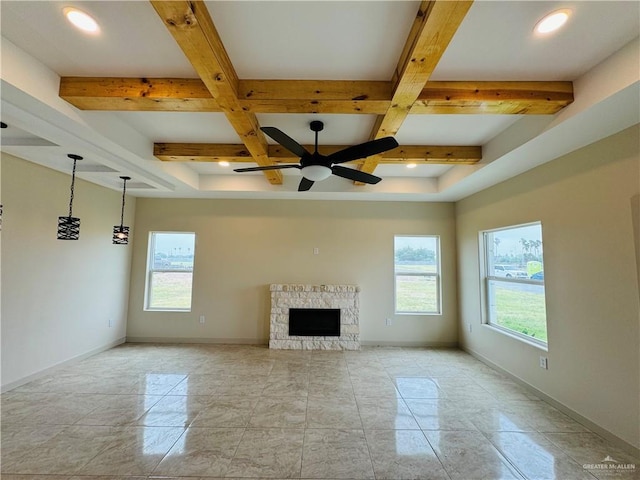 unfurnished living room featuring ceiling fan, a healthy amount of sunlight, beam ceiling, and a fireplace