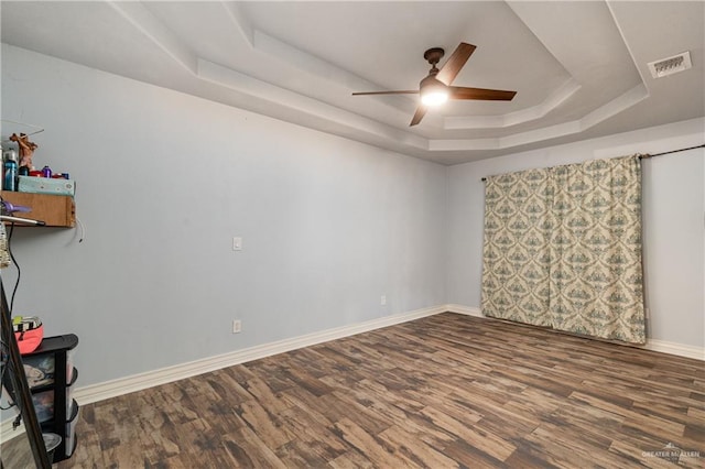 empty room featuring ceiling fan, a raised ceiling, and hardwood / wood-style floors