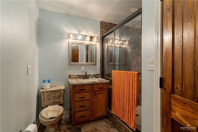 bathroom featuring vanity, toilet, and a shower with shower door