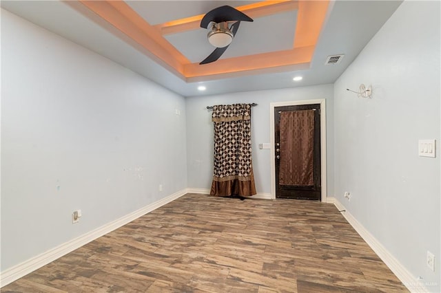 unfurnished bedroom featuring hardwood / wood-style floors, a raised ceiling, and ceiling fan