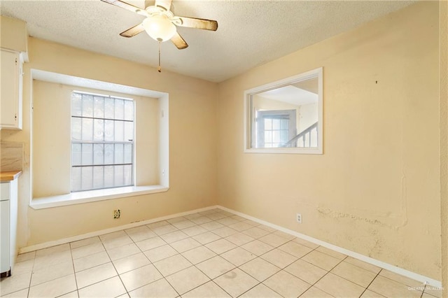 tiled spare room with a textured ceiling and ceiling fan