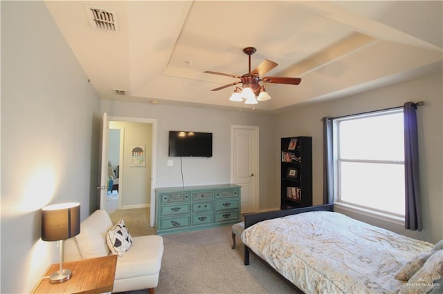 carpeted bedroom with a tray ceiling and ceiling fan