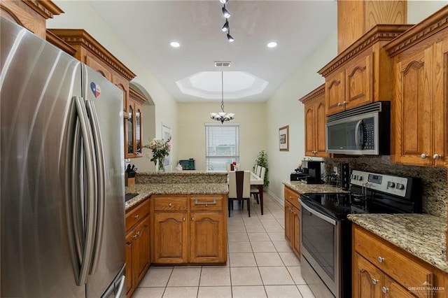 607 Via Cantera Dr, San Juan, TX 78589 - kitchen featuring appliances with stainless steel finishes, light tile patterned flooring, brown cabinetry, and a skylight