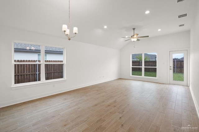 unfurnished room featuring vaulted ceiling and ceiling fan with notable chandelier