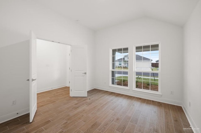 unfurnished bedroom featuring vaulted ceiling, light hardwood / wood-style floors, and multiple windows