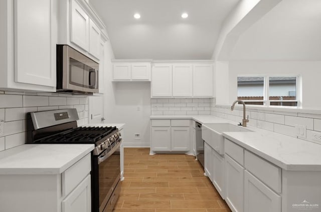 kitchen featuring decorative backsplash, appliances with stainless steel finishes, white cabinetry, and sink