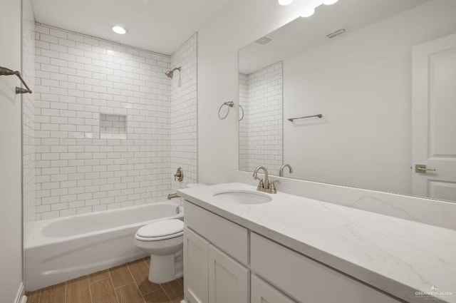 full bathroom featuring tiled shower / bath combo, toilet, and vanity