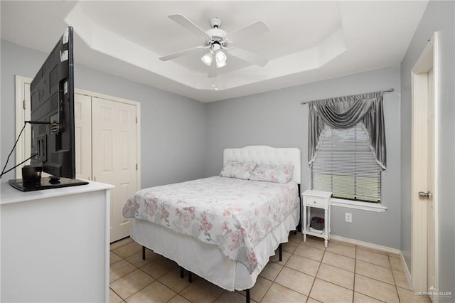 tiled bedroom with a closet, ceiling fan, and a tray ceiling