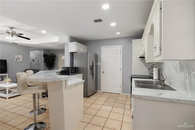 kitchen featuring a kitchen bar, white cabinets, light tile patterned flooring, and appliances with stainless steel finishes