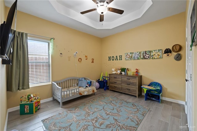 9713 Alexis Ave, Harlingen, TX 78552 - bedroom with a tray ceiling, baseboards, a nursery area, and ceiling fan