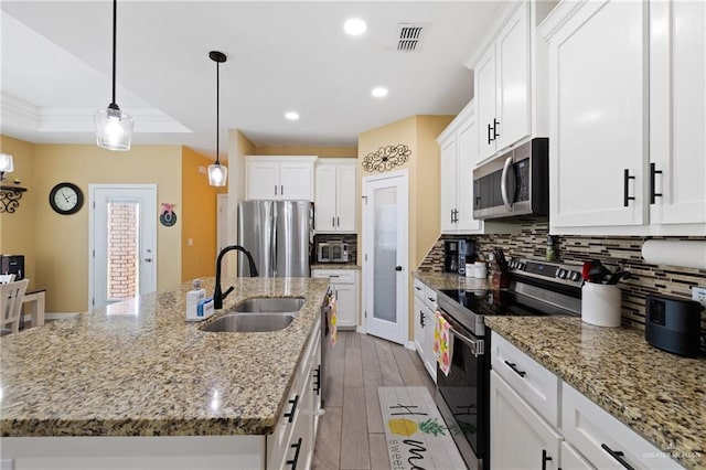 9713 Alexis Ave, Harlingen, TX 78552 - kitchen with stainless steel appliances, a sink, a center island with sink, decorative backsplash, and white cabinets