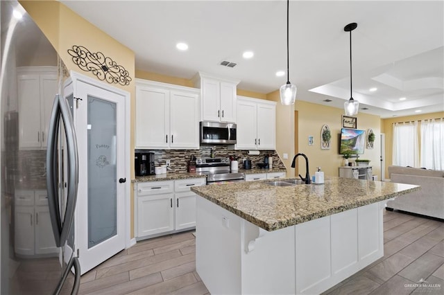 9713 Alexis Ave, Harlingen, TX 78552 - kitchen featuring stainless steel appliances, a sink, backsplash, wood finish floors, and open floor plan