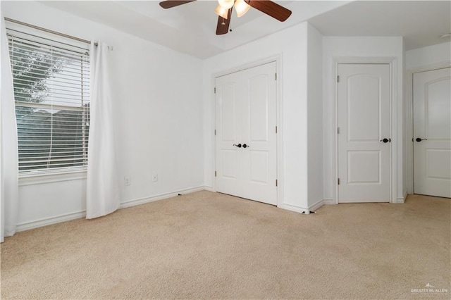 unfurnished bedroom with a ceiling fan, light carpet, and baseboards