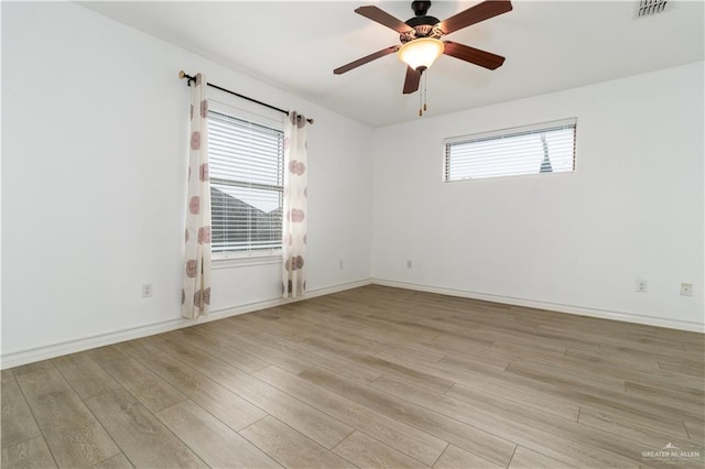 unfurnished room featuring plenty of natural light, light wood-style flooring, visible vents, and ceiling fan