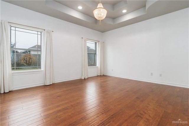 unfurnished room with baseboards, a tray ceiling, a chandelier, and wood finished floors