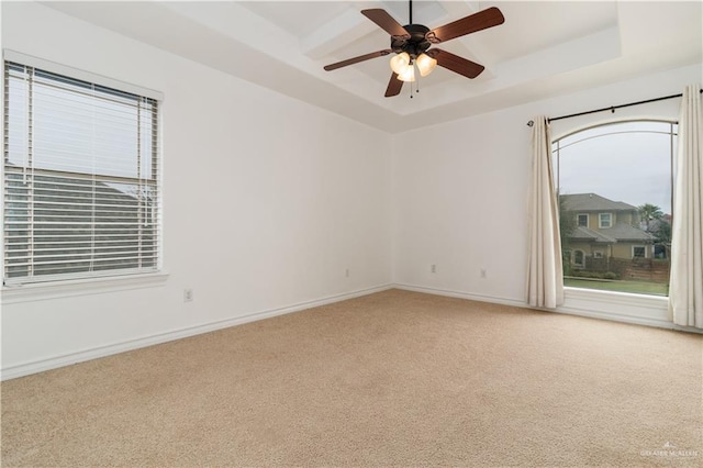 carpeted empty room with baseboards, a tray ceiling, and ceiling fan