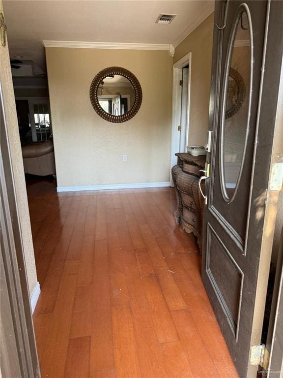 hall featuring light wood finished floors, visible vents, and crown molding